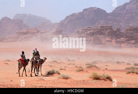 Les gens sur des chameaux en passant par la tempête du désert Banque D'Images