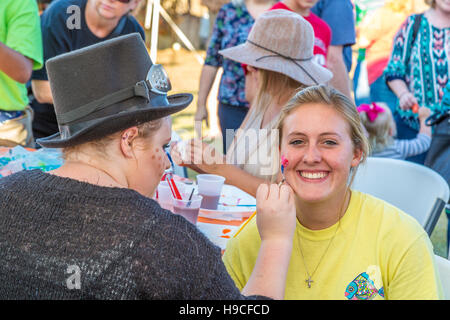 Young woman getting son visage peint à un festival d'automne à Gulfport, Mississippi Banque D'Images