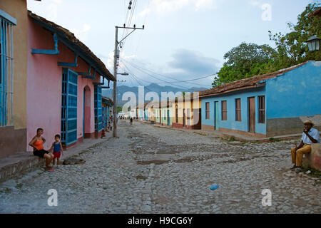 À la recherche dans une rue de Trinidad Cuba avec colouful peint pastel maisons et des habitants assis Banque D'Images