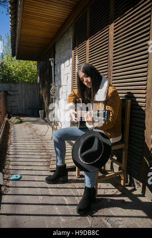 Cowgirl posent avec une guitare dans une maison de ferme Banque D'Images