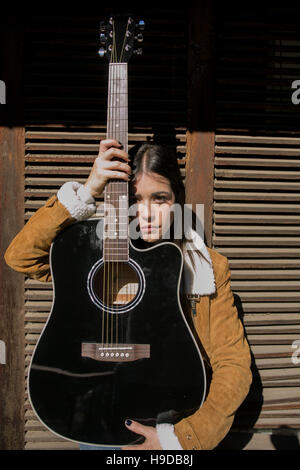 Cowgirl posent avec une guitare dans une maison de ferme Banque D'Images