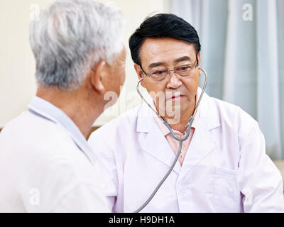 Contrôle d'un médecin de l'Asie l'aide senior patient with stethoscope Banque D'Images