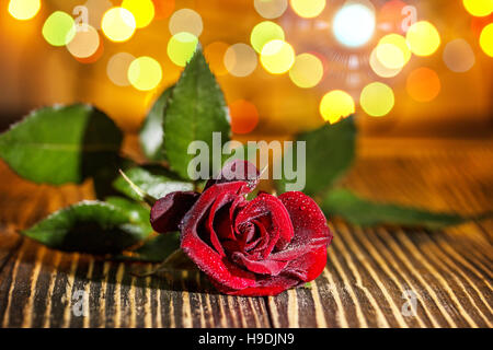 Verre de whisky écossais et de glace , rose rouge dans l'arrière-plan flou coloré de vacances sur table en bois Banque D'Images