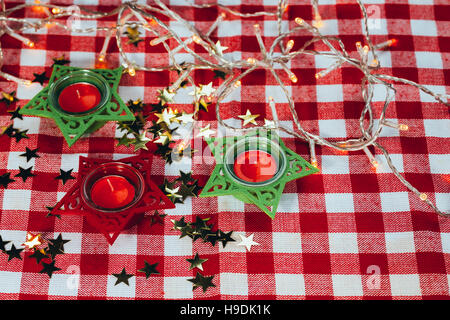 Bougie sur nappes à carreaux rouges et Garland. Banque D'Images