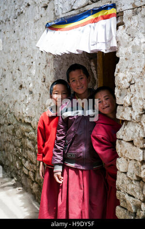 Trois moines novices se tenir en face d'une porte à leur monastère dans la vallée de Tawang à distance, de l'Inde. Banque D'Images