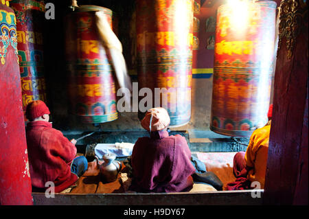 Moines au monastère de Tawang grand spin roues de prière tout en chantant des prières bouddhistes dans la vallée de Tawang à distance, de l'Inde. Banque D'Images