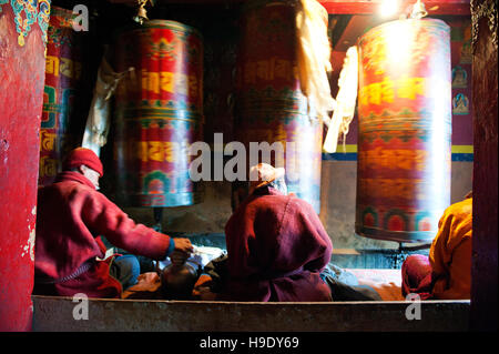 Moines au monastère de Tawang grand spin roues de prière tout en chantant des prières bouddhistes dans la vallée de Tawang à distance, de l'Inde. Banque D'Images