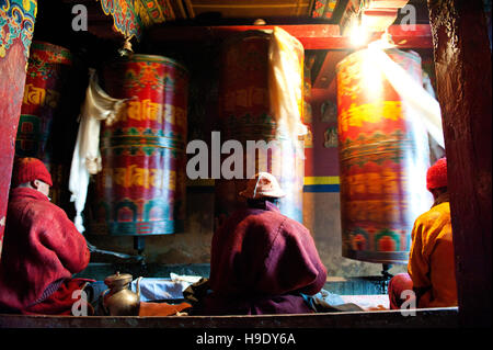 Moines au monastère de Tawang grand spin roues de prière tout en chantant des prières bouddhistes dans la vallée de Tawang à distance, de l'Inde. Banque D'Images