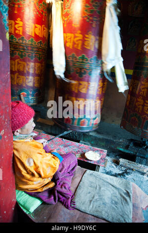 Moines au monastère de Tawang grand spin roues de prière tout en chantant des prières bouddhistes dans la vallée de Tawang à distance, de l'Inde. Banque D'Images