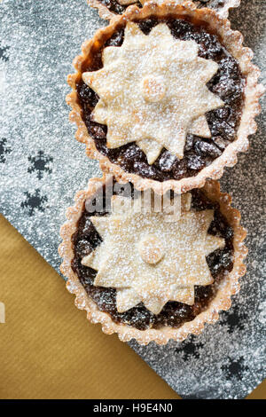 Tartes Tarte au mincemeat noël, décorée d'une étoile et saupoudrés de sucre glace sur l'ardoise et fond d'or Banque D'Images