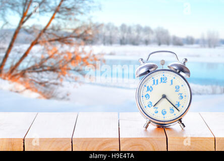 Vintage réveil sur table en bois ou un banc sur l'arrière-plan la saison d'hiver. Retour à l'heure d'hiver. Tomber en arrière du temps. Fin de l'heure d'été Banque D'Images