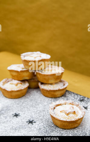 Tartes Tarte au mincemeat noël, décorée d'une étoile et saupoudrés de sucre glace sur l'ardoise et fond d'or Banque D'Images