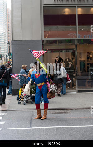 Un vendeur de rue afro-américain sur un costume de superman la vente de sacs à main et des drapeaux américains à New York City Banque D'Images