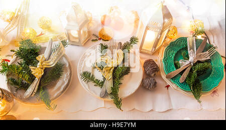 Table de fête Noël Décoration réglage avec vaisselle,branches de sapins, ruban, lanterne avec des bougies Banque D'Images