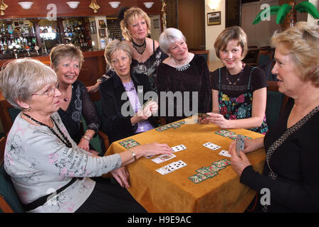 Un groupe de sept femmes joueurs de bridge, assis autour d'une seule table. Banque D'Images