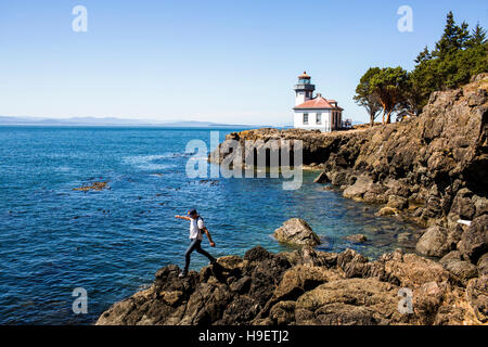 Caucasian man walking on rocks près de lighthouse Banque D'Images