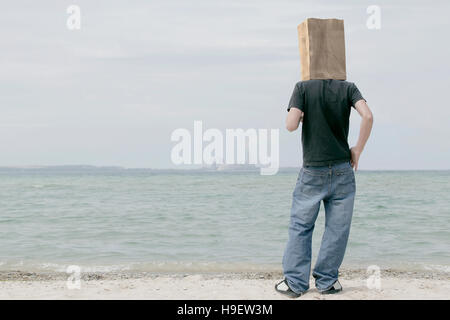 Homme portant un sac de papier sur la tête en regardant l'horizon lointain Banque D'Images