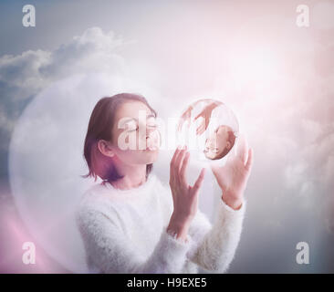 Mixed Race girl dans les nuages holding glass sphere Banque D'Images