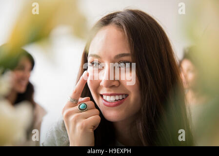 Smiling woman applying moisturizer à face Banque D'Images