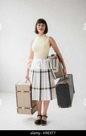 Portrait of smiling Hispanic woman holding valises Banque D'Images