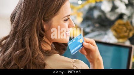 Portrait of young woman with credit card and laptop in front of Christmas Tree Banque D'Images