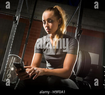 Caucasian woman texting on cell phone in gymnasium Banque D'Images