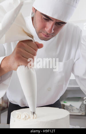 Hispanic chef decorating cake Banque D'Images