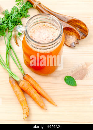 Verres de jus de carotte avec racines de carottes sur fond de bois.G Banque D'Images