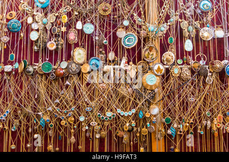 Bon nombre des chaînes en or accroché contre un mur sur fond rouge Banque D'Images