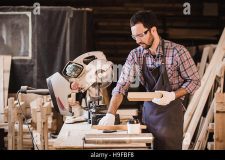 Profession, menuiserie, menuiserie - Menuisier concept les gens avec la planche en bois et ses notes de contrôle de l'ordinateur portable en atelier Banque D'Images