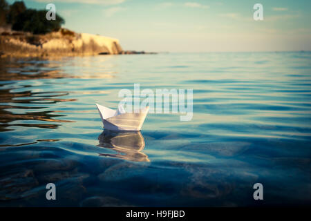 Bateau de papier flottant dans la mer. Tonique Photo. Banque D'Images