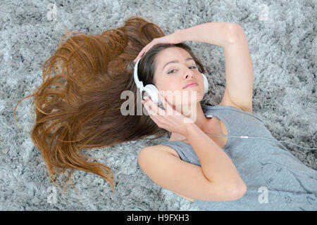 Jeune brunette woman listening music tout en posant sur le tapis Banque D'Images