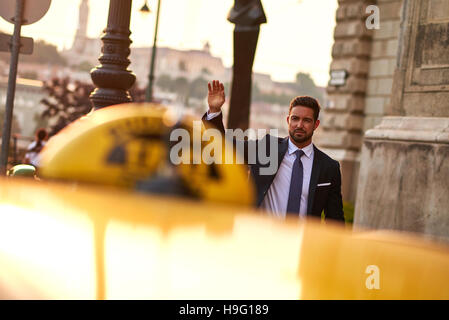 Un beau jeune businessman waving pour un taxi Banque D'Images