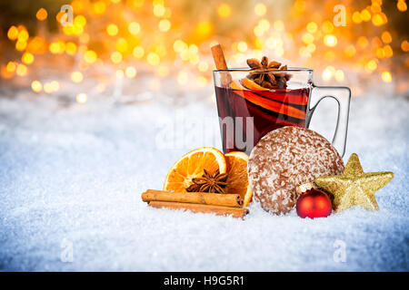 Vin rouge épicé chaud dans la tasse en verre avec gingerbread tranche d'orange noël décoration allumé les lumières vives bokeh background Banque D'Images