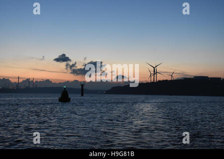 Un autre beau coucher du soleil à Milford Haven avec les nuages dans un ciel bleu et rouge, les éoliennes, et les bouées de navigation lights Banque D'Images