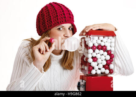 Jeune femme tenant un chewing-gum, à côté d'un gumball machine Banque D'Images