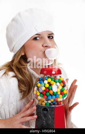 Jeune femme de mâcher de la gomme, à côté d'un gumball machine Banque D'Images