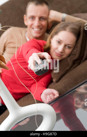 Couple lying on a couch watching TV Banque D'Images