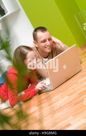 Couple allongé sur le plancher du salon, travailler sur un ordinateur portable Banque D'Images