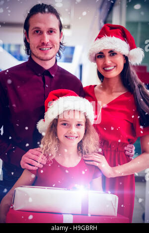 Image composite de la famille dans une tenue de noël debout avec les cadeaux de Noël Banque D'Images