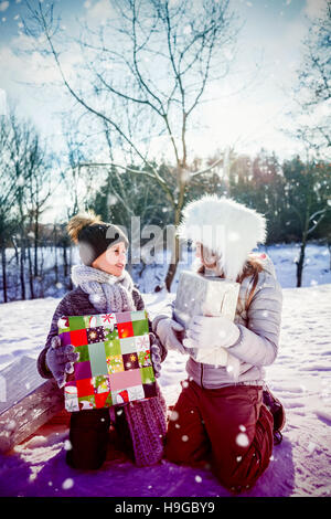 Image composite de brother sister holding présente tout en s'agenouillant en champ de neige Banque D'Images