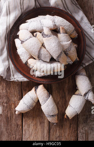 Rouleaux de croissant avec les graines de pavot macro sur une assiette sur la table. vertical Vue de dessus Banque D'Images