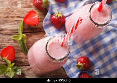 Lait frappé aux fraises fraîches dans des bouteilles en verre sur la table. Vue du dessus horizontale Banque D'Images