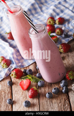 Smoothie aux fraises et bleuets dans des bouteilles sur la table verticale. Banque D'Images