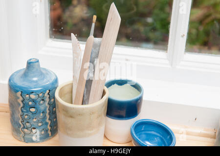 Outils et des vases de poterie sur un rebord de fenêtre à la lumière du jour Banque D'Images