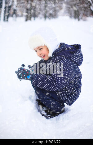 Petite fille jouant avec la neige dans un parc. Merveilleux Jour de neige. Le concept de l'enfance et de la saison d'hiver. Banque D'Images