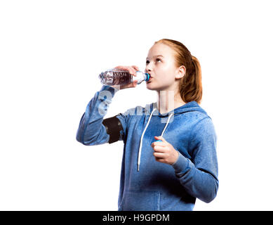 Adolescente de boire une bouteille d'eau. Studio shot, isolé. Banque D'Images