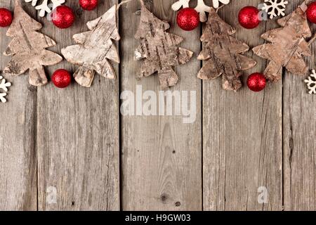 Noël rustique en bois avec bordure supérieure des ornements et des boules rouges sur un fond de bois de Banque D'Images