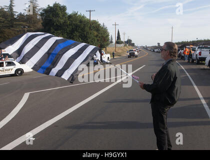 Modesto, CA, USA. 22 Nov, 2016. Tom Powell de Waterford CA tenir un drapeau comme un défilé de voitures de patrouille entrer dans le cimetière près de Lakewood Hughson, CA. Adjoint du shérif du comté de Stanislaus Dennis Wallace a été honoré par sa famille et amis de partout aux États-Unis au point Croix Église de Modesto CA Le mardi 22 novembre 2016. Adjoint du shérif du comté de Stanislaus Dennis Wallace a été tué dans l'exercice de leurs fonctions 13 Nov. 2016 près de Hughson CA. © Marty Bicek/ZUMA/Alamy Fil Live News Banque D'Images