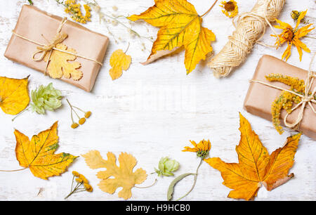 Composition de cadeaux et de feuilles jaunes sur un fond en bois blanc automne concept. Banque D'Images